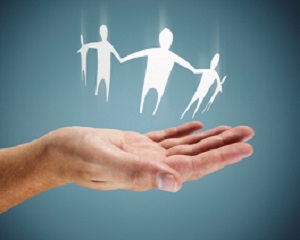 A family of paper doll cut-outs hovers over the palm of a hand.