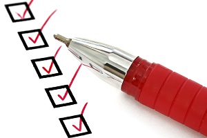 A red pen sits on a paper with five checked boxes.