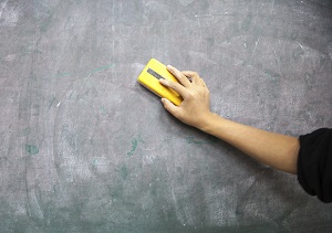 Hand erasing writing on a chalkboard