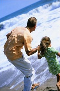 Father playing in waves with daughter