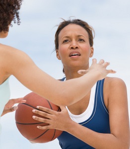 A woman looks for an opportunity to pass a basketball.