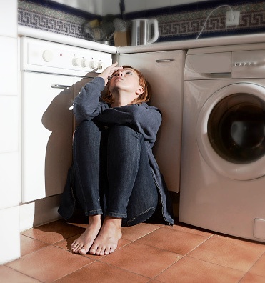 young depressed woman sitting on kitchen floor sad and wasted