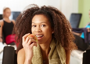 A woman takes a break at the gym and bites into an apple.