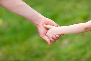 A child's hand is in an adult's hand.