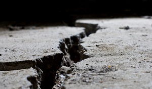 A close-up picture of a large crack in concrete pavement.