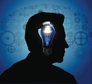 A man's silhoutted head has an illuminated light bulb in it.