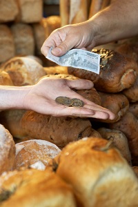 A market stallholder handing change to customer buying bread.