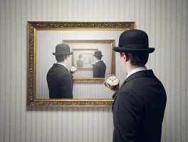A man holding a small clock looks at a painting with a repeating mirror image of himself.