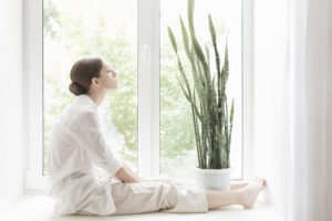 Person sitting by window looking up meditating