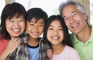 A smiling nuclear family pose close to each other.