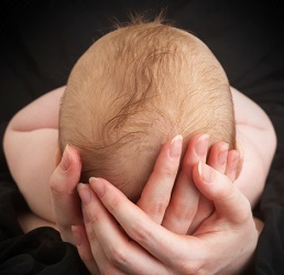 Hands cradle baby's head