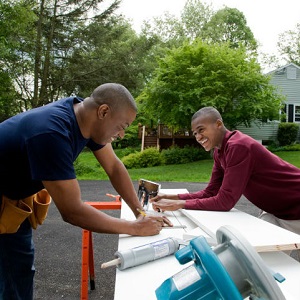 A father and his teenage son do woodworking together.