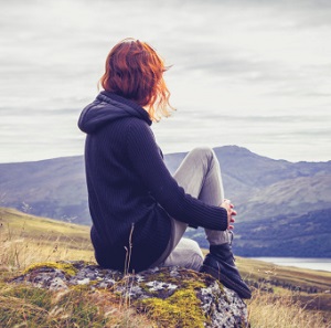 Woman surveys the view from atop a hill.