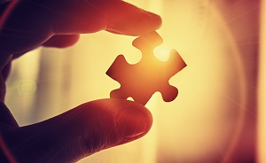 Backlit hand holding puzzle piece
