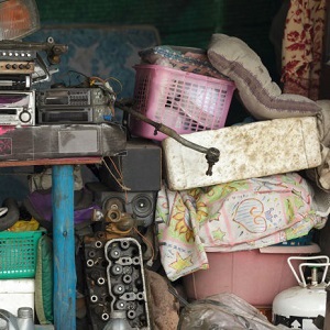 Many broken and useless items are cluttered together, piled up along a wall.