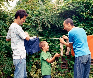 Boy and two men hanging out laundry