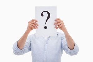 Man holding question mark in front of his face