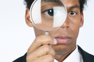 Man holding magnifying glass over eye