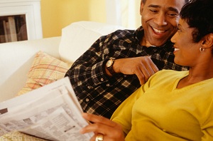 Couple sitting on couch reading the paper