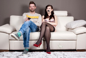 Couple on couch with woman's mouth taped