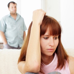 Unhappy woman looks down while distressed partner looks on