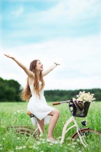 Happy woman riding bike through flowers