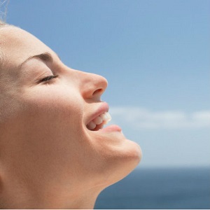 A close-up picture of a woman's face shows her smiling and breathing deeply. 