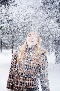 A woman happily plays in the snow alone.