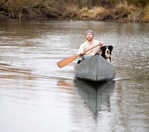 Young man and his dog canoeing