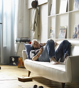 A man relaxes on a couch with music.