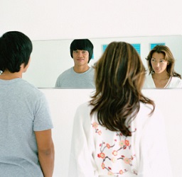 Woman and man study one another in the mirror