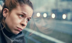 Woman looks thoughtfully out train window