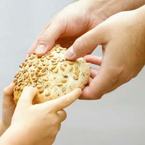 A piece of break is passed between a man's hands and a child's.