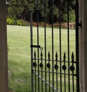 An iron gate opens onto a grassy scene.