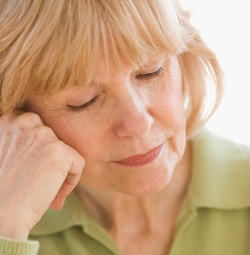 A middle-aged woman rests her head on her hand