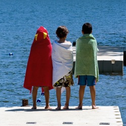 Three kids in swim suits on dock