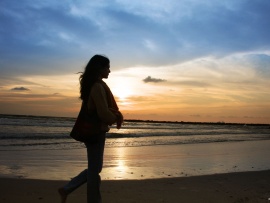 Woman walking on beach at sunset