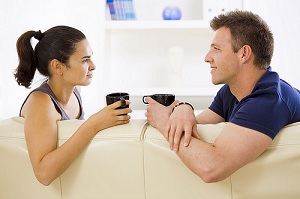 A couple having coffee together on a couch.