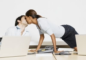 Coworkers kissing over desk