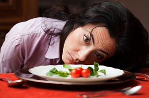 Woman staring at plate with tiny salad