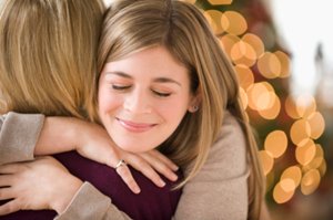 A young woman smilingly hugs an older mentor.