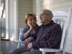 Old man and adult daughter sitting on porch chairs