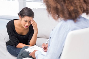 A young woman with a sad look on her face talks to her therapist.