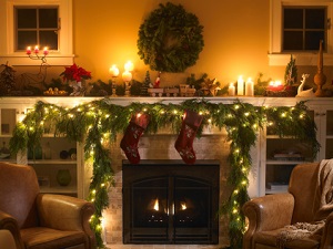 Christmas decorations, a wreath, lights, and stockings, decorate a fireplace.