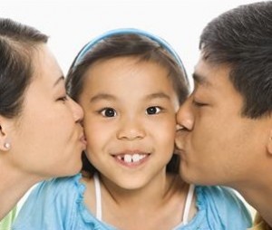 Mother and father kissing daughter's cheeks