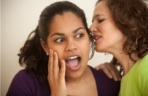 Woman whispering secret to surprised woman