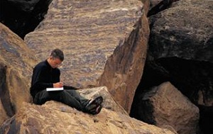 Man sitting on rocks journaling
