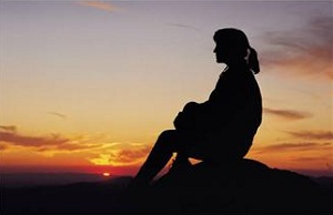 Silhouette of woman sitting at sunset