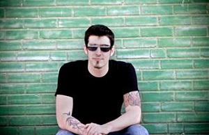Man with sunglasses crouching in front of brick wall