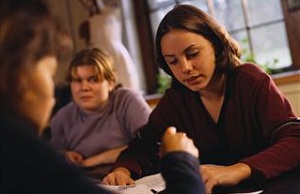 Teens studying with unhappy girl in background